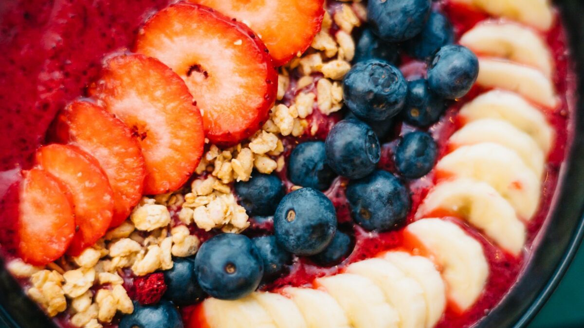 Bát smoothie acai màu tím với dâu tây, việt quất, chuối và granola