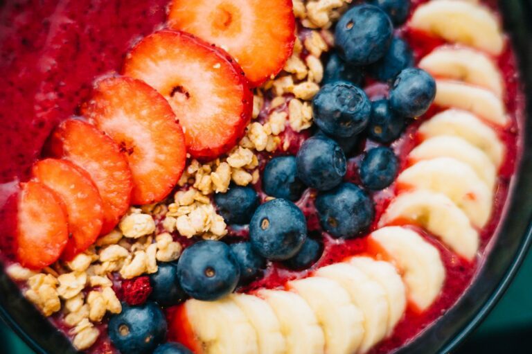 Bát smoothie acai màu tím với dâu tây, việt quất, chuối và granola