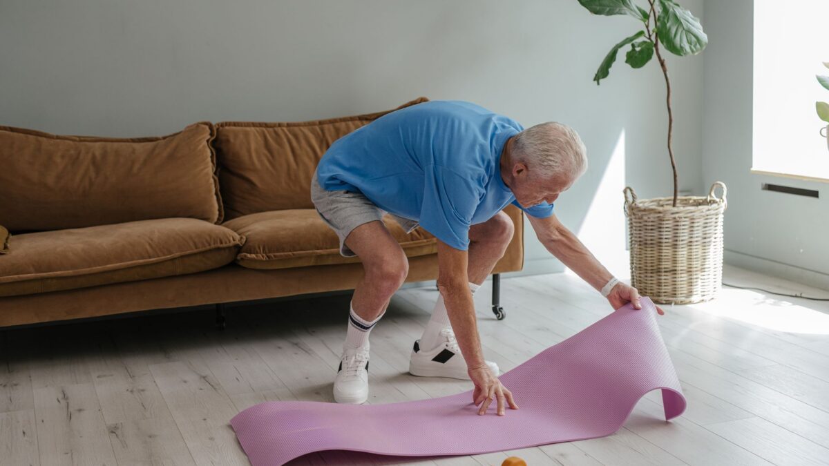 Người cao tuổi đang trải thảm yoga trong nhà